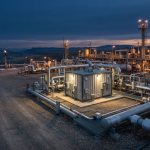 Remote natural gas processing facility with an analyzer shelter at dusk